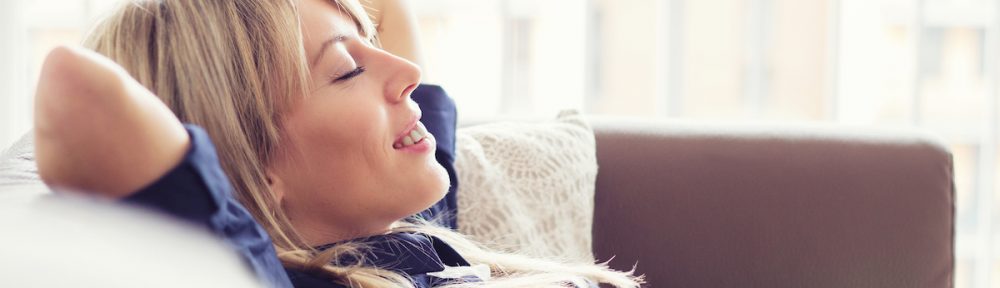 Woman relaxes on couch in a home with a comfortable temperature.