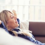 Woman relaxes on couch in a home with a comfortable temperature.