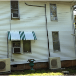 Ductless AC installed on side of house from window.