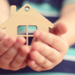 person holding a wood cutout of a home